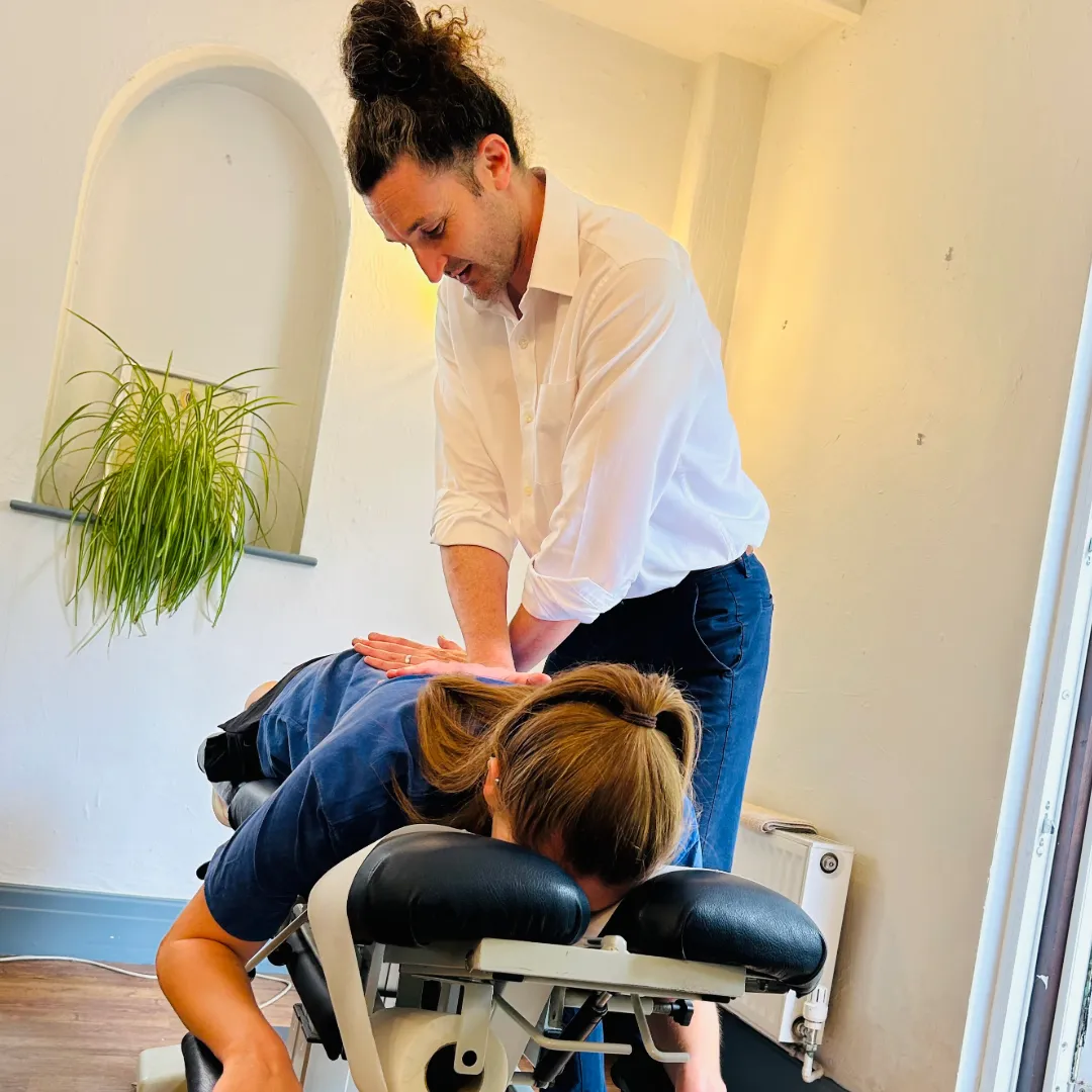 Chiropractor performing back adjustment therapy on patient.